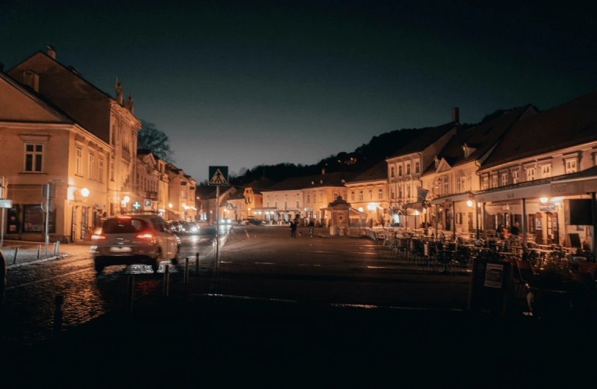 Rua iluminada de Zagreb à noite, com restaurantes e cafés ao longo de uma charmosa praça.