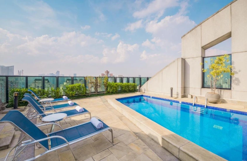 Durante o dia, cobertura de hotel com piscina, espreguiçadeiras e plantas ao redor