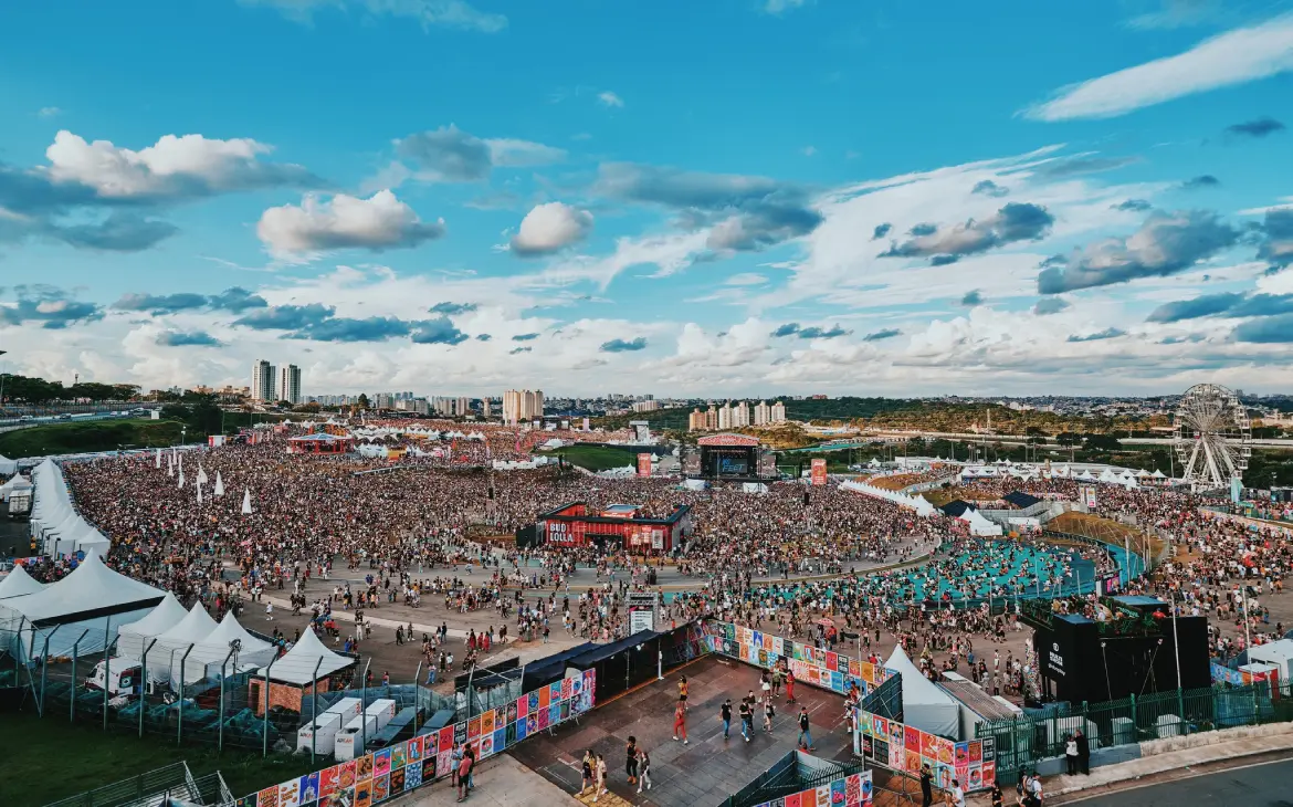 Em um dia de sol, vista aérea do Lollapalooza com pessoas, barracas e palcos