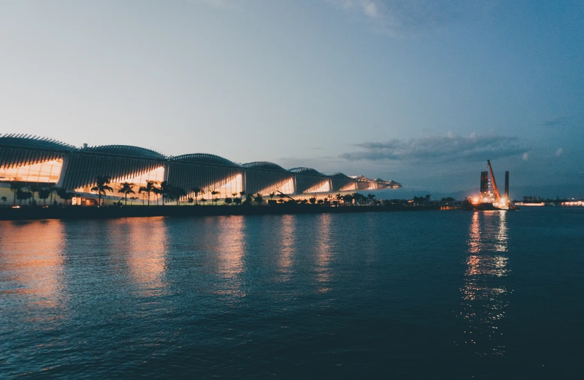 Museu do Amanhã, no Rio de Janeiro, com sua arquitetura moderna iluminada, refletida nas águas da Baía de Guanabara.