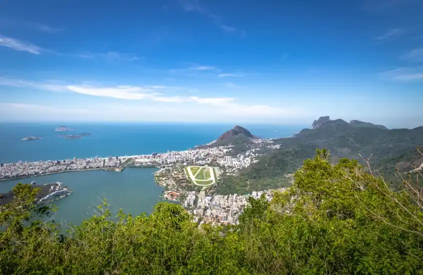 Vista ampla da Lagoa Rodrigo de Freitas cercada por áreas urbanas, incluindo o Jardim Botânico e o Jockey Club Brasileiro.