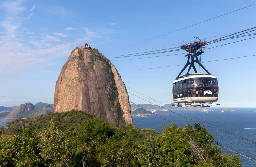 Bondinho do Pão de Açúcar subindo em direção ao famoso morro, com céu azul ao fundo.