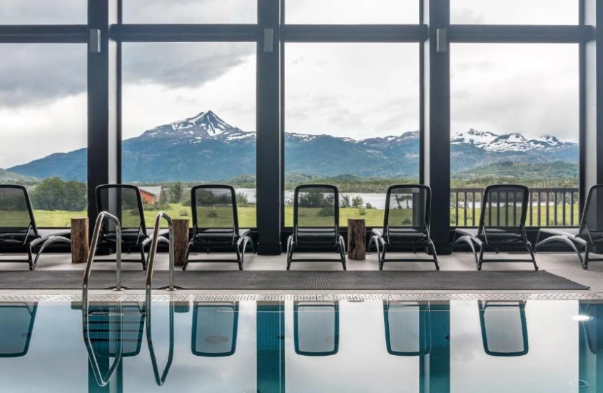 Piscina interna com vista para montanhas cobertas de neve.