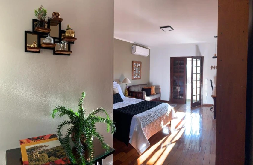 Quarto decorado com detalhes rústicos e modernos, incluindo uma planta ornamental e móveis de madeira.