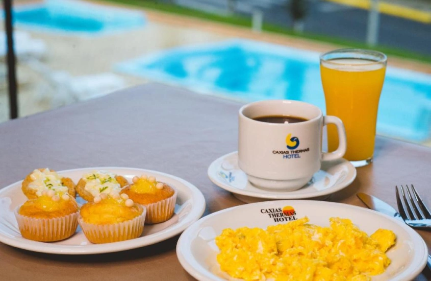 Mesa de café da manhã em frente a área de lazer com piscinas