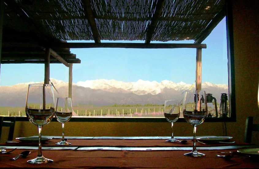 Mesa com taças de vinho e paisagem das montanhas