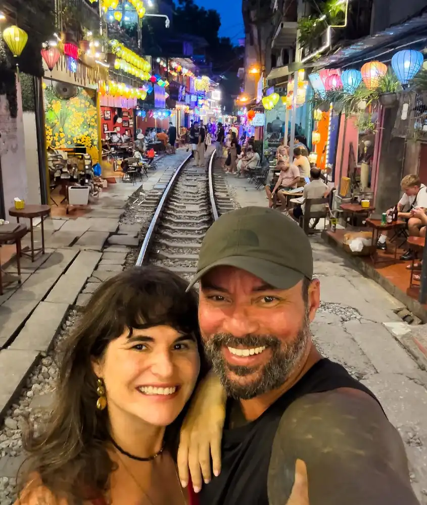 Vagner e Barbara nas ruas de Old Quarter com lojinhas ao redor e trilho de trem