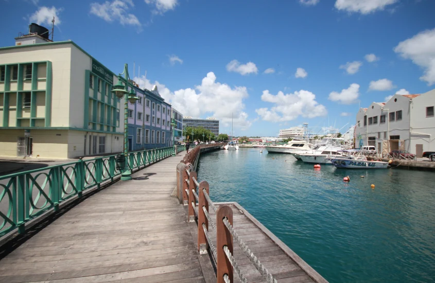 Durante o dia, cominho de madeira com grades, canal do lado e prédios ao redor