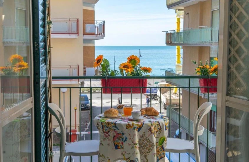 Paisagem de varanda com mesa, cadeiras, vista da praia e flores decorativas