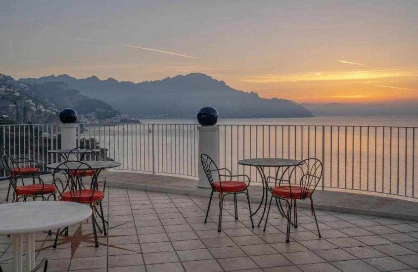 Cobertura de hotel com mesas, cadeiras, praia na frente e ilha na frente