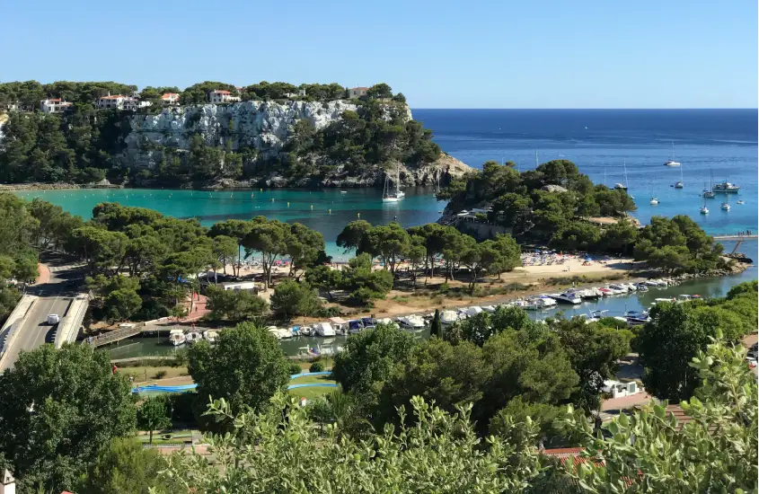 Em um dia de sol, vista aérea de menorca com mar, árvores e barcos ao redor