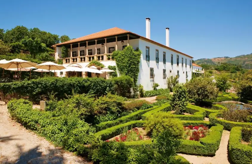 Fachada de hotel com plantas ao redor e piscina atrás