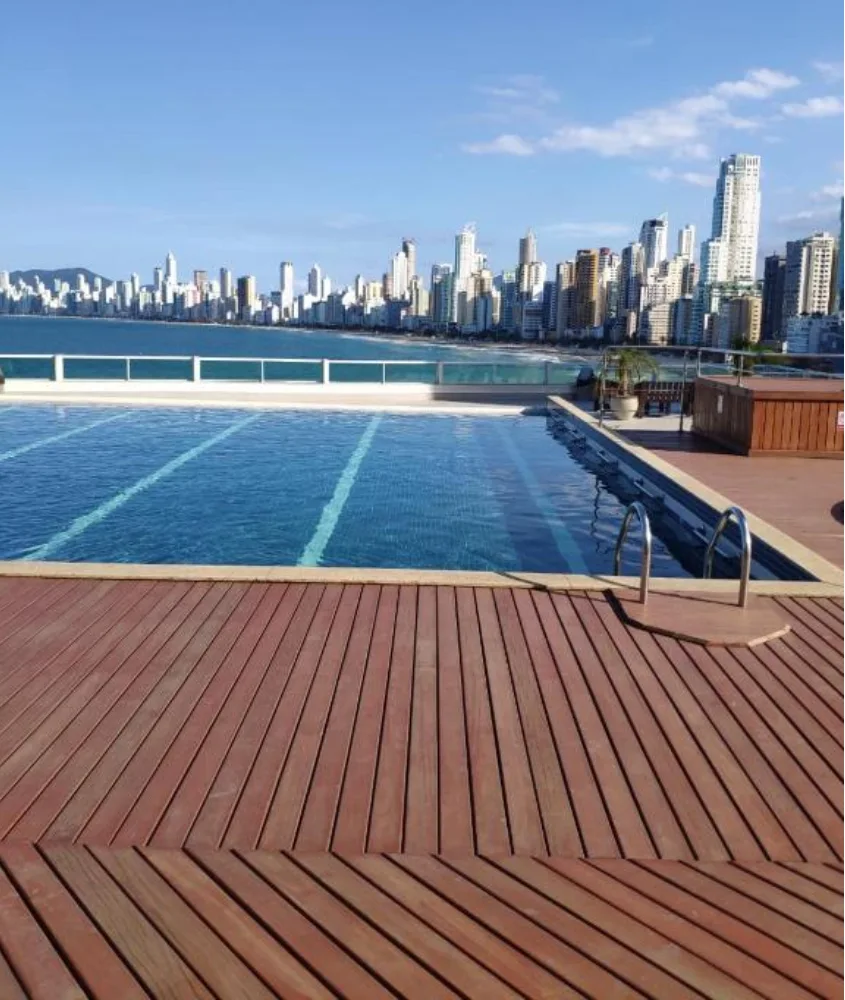 Em um dia de sol, piscina na cobertura, deck de madeira e praia do lado