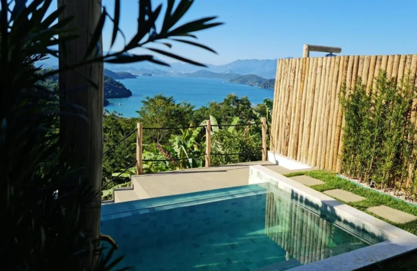 Em um dinal de tarde, área de piscina de hotel com vista para o mar, árvore e plantas ao redor