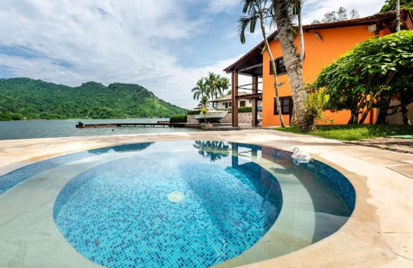 Durante o dia, área de lazer de hotel com piscina, praia e árvores ao redor