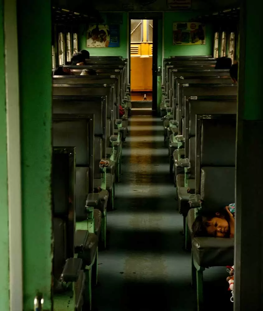criança deitada em banco de trem em Bangkok