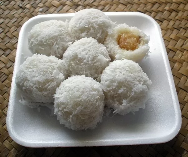 bolinhas de Khanom tom, uma mistura de farinha de arroz glutinoso e água, enroladas em coco ralado, em cima de vasilha e isopor