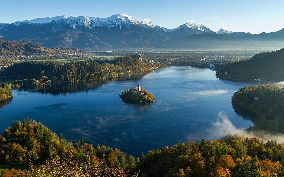vista aérea de lagoa rodeada de árvores e colinas na eslovenia