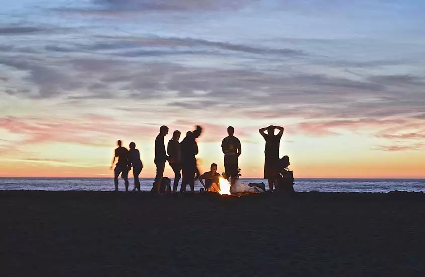 povo da nova Zelândia reunido em praia durante entardecer, uma atividade legal a se fazer ao morar na nova Zelândia