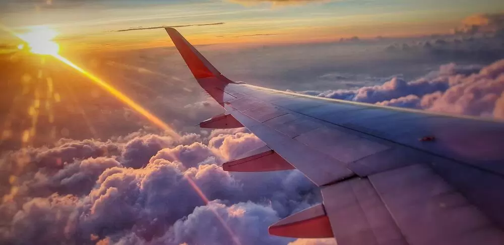 Asa de avião acima de nuvens durante o entardecer