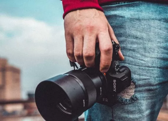 Fotógrafo segura câmera para fotografar, uma das formas de ganhar dinheiro viajando