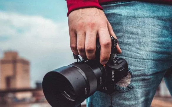 Fotógrafo segura câmera para fotografar, uma das formas de ganhar dinheiro viajando