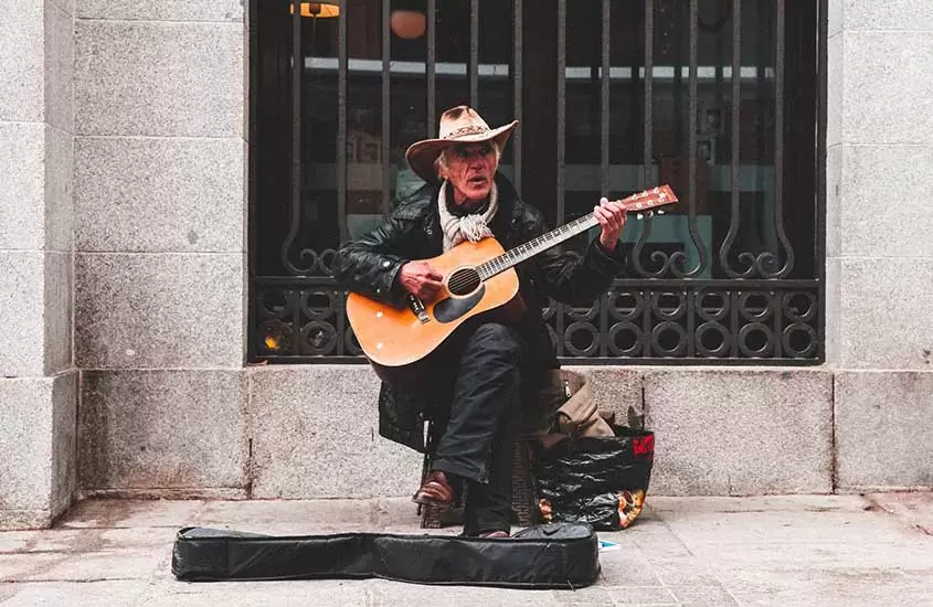 Músico toca violão em uma rua, durante o dia