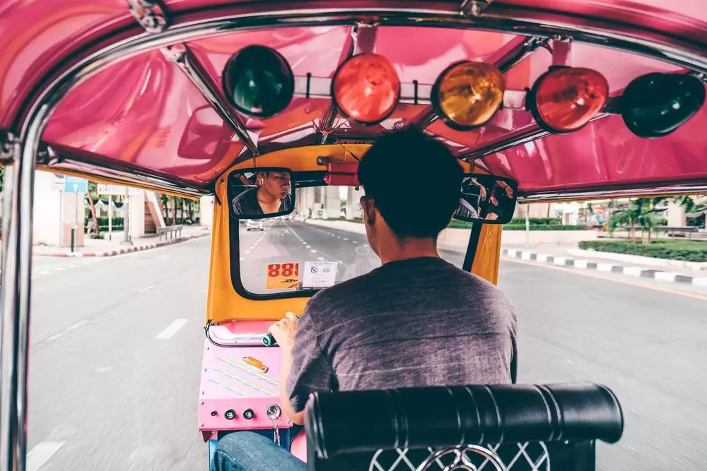 Homem dirige tuk tuk, durante o dia, em Bangkok, capital da Tailândia