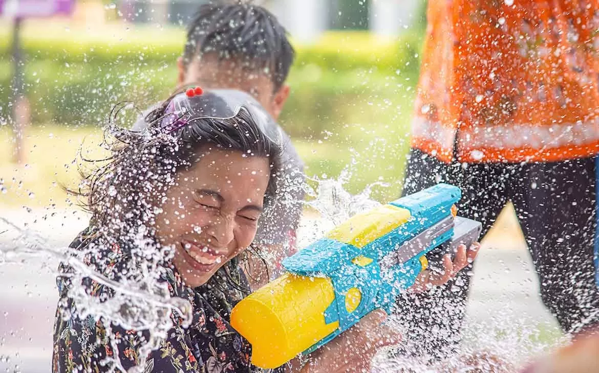 Mulher sorri enquanto dispara arminha de água em uma luta de água, conhecida como “Songkran”, um dos festivais mais divertidos do mundo, que acontece na Tailândia