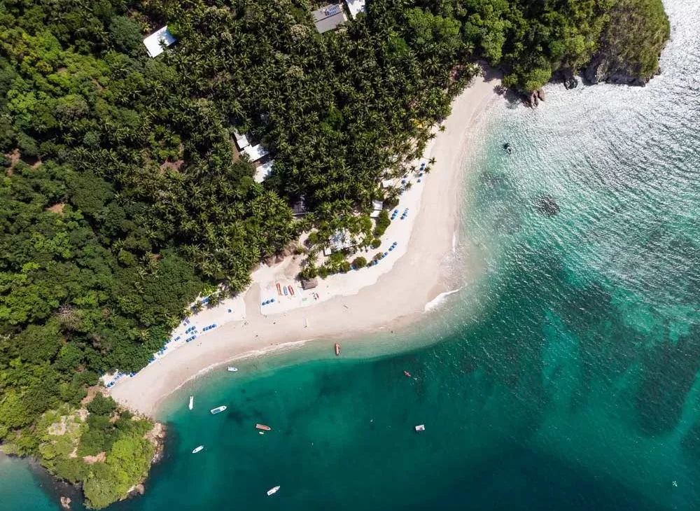 Vista área, durante o dia, do mar, e vegetação da Ilha Tortuga, localizada no Haiti, um dos lugares para viajar barato