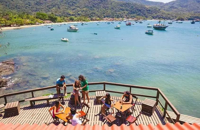 viajantes conversam em deck de hostel em Ilha Grande em frente ao mar