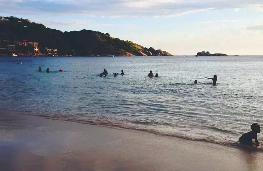 Pessoas tomando banho de mar durante o dia, uma das opções entre muito o que fazer em Barra de Guaratiba