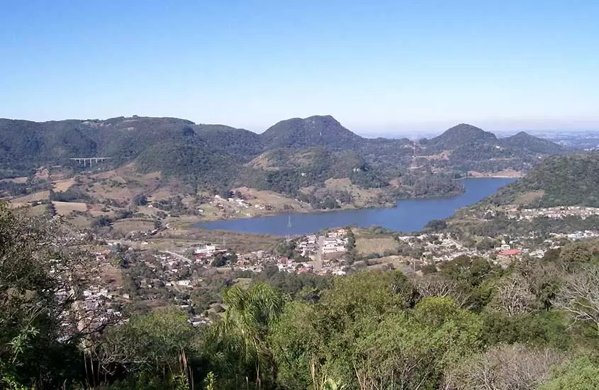 Vista aérea de montanhas e casas ao redor de lagoa, durante o dia em Santa Maria, um dos lugares para viajar no Rio Grande do Sul