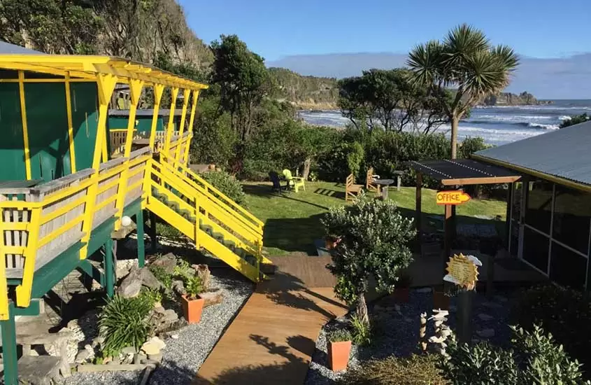 cadeiras, mesas e plantas em pátio do Punakaiki Beach, um hostel nova zelandia em frente à praia