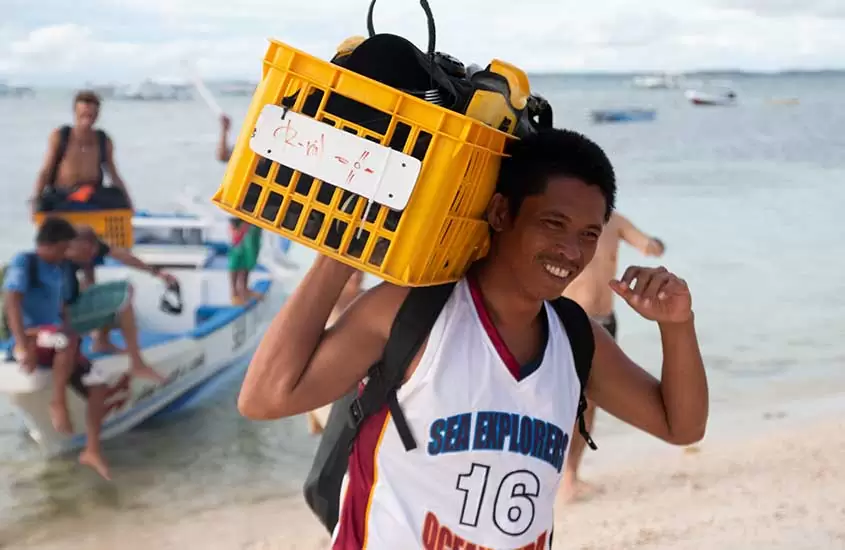 homem carrega caixa com equipamentos de mergulho