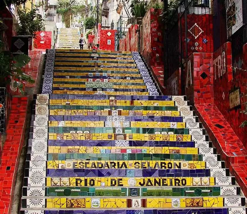 pessoas descem escada colorida de azulejos, conhecida como Escadaria Selarón, no centro do rio de janeiro