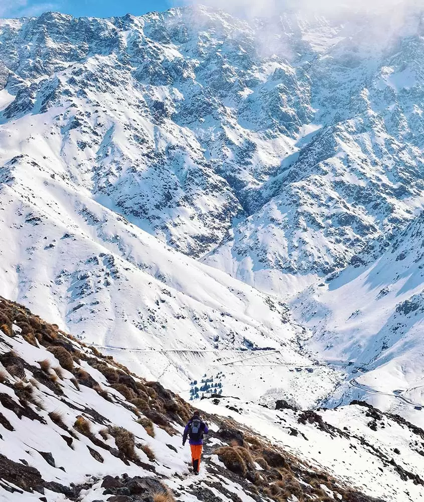 Homem caminha em montanha cheia de neve. Uma das curiosidades do Marrocos é que há tempestades de neve