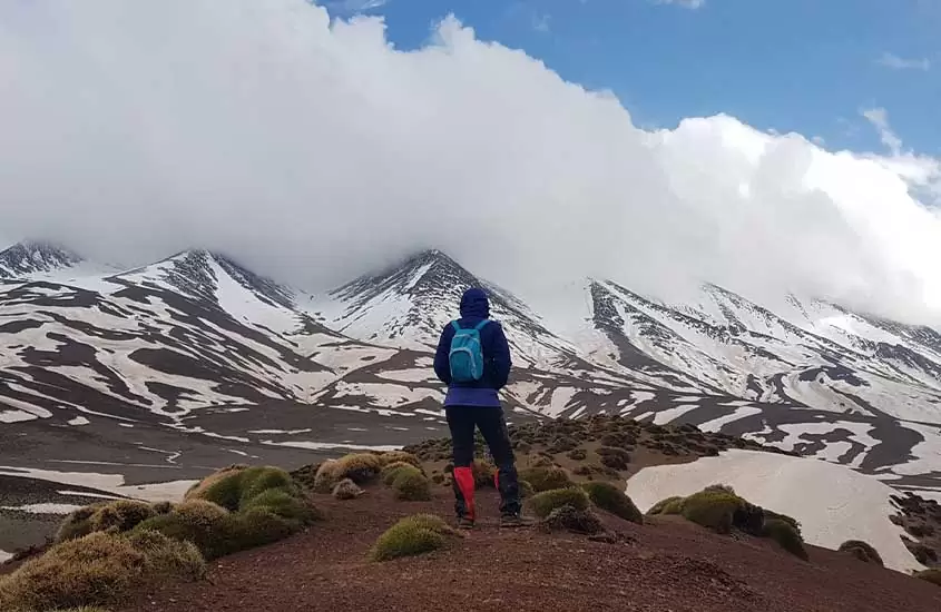 homem olha para montanha com neve no Marrocos
