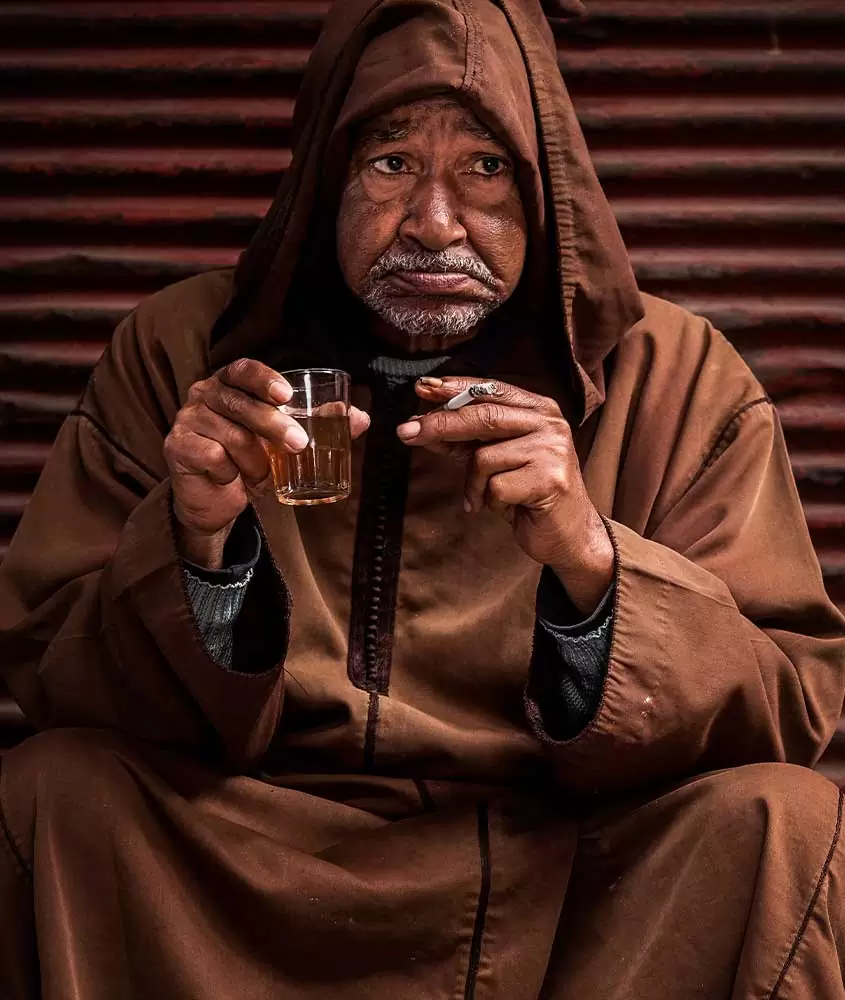 Homem segura copo de cerveja e cigarro. Uma das curiosidades sobre o Marrocos é que é difícil encontrar álcool