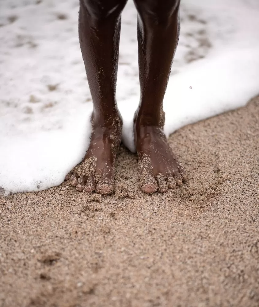 pés descalços na areia da praia, molhados pelo mar