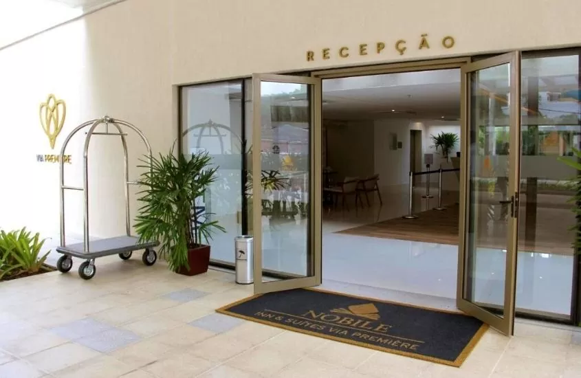 Plantas, tapete e porta de vidro aberta em entrada do hotel Nobile Inn Via Premiere