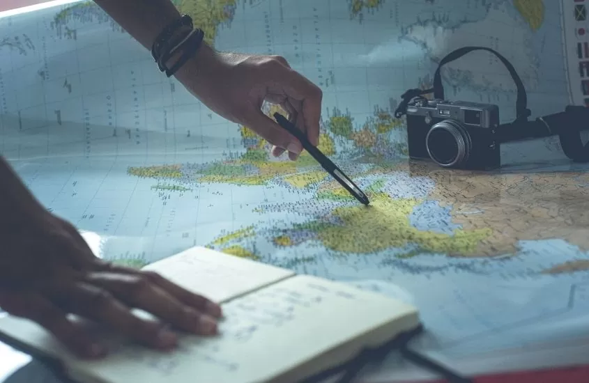 Pessoa anotando informações de mapa para planejar uma viagem