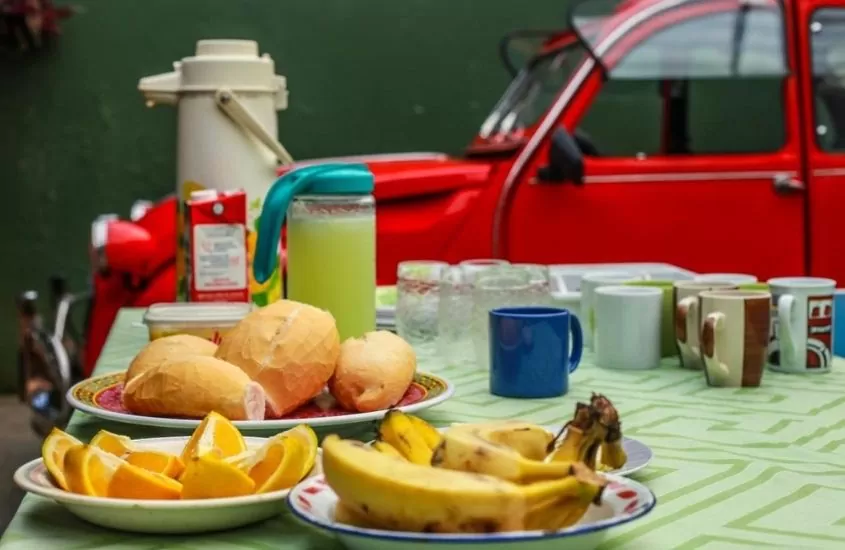 pães, frutas e sucos em mesa de café de Hostel Trindade, uma opção para quem busca onde ficar em Trindade