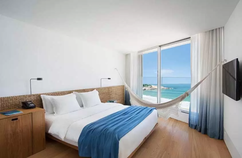 cama de casa, rede de descanso e televisão em quarto com vista para o mar em Hotel Arpoador, uma opção de onde ficar no rio de janeiro