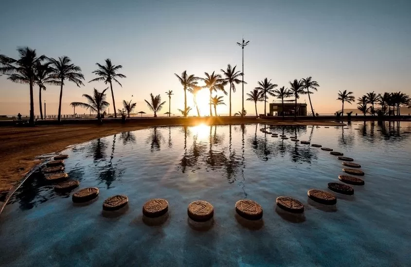 piscina, coqueiros e areia em Durban durante o pôr do sol