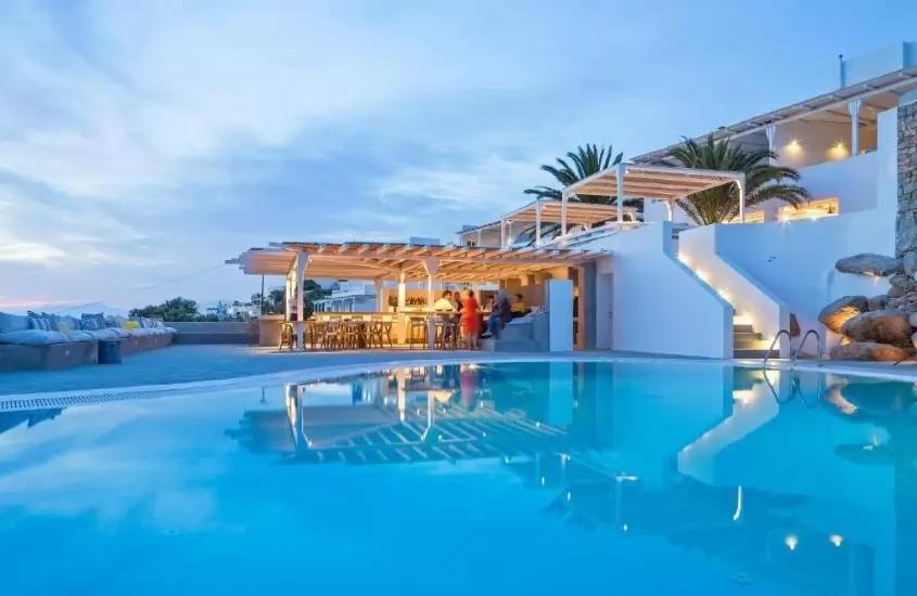 piscina, cadeiras, mesas e sofá em área de lazer de boheme mykonos, um hotel paradisíaco em uma das ilhas gregas