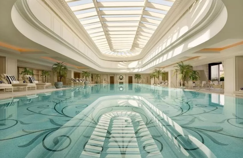 piscina coberta cercada de espreguiçadeiras e vasos com planta em área de lazer de the peninsula shanghai, hotel na china