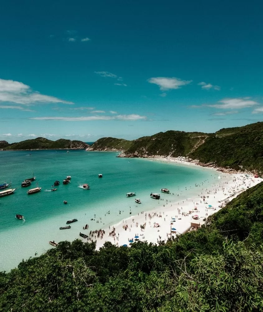 barcos em mar e pessoas na areia de praia em Arraial do Cabo, um dos lugares mais bonitos do Rio de Janeiro