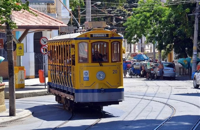 pessoas em bondinho amarelo em rua de Santa Tereza, no Rio de Janeiro