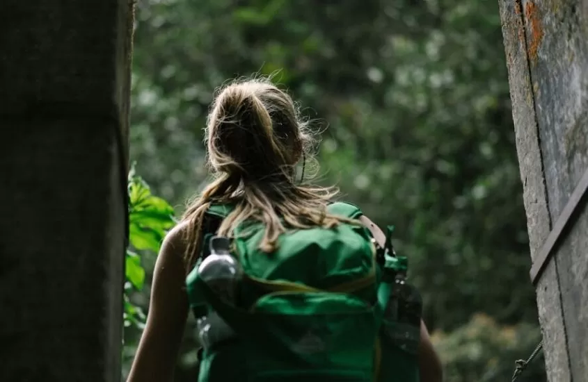 Viajante com mochila verde caminha em Parque ecológico em Sana RJ